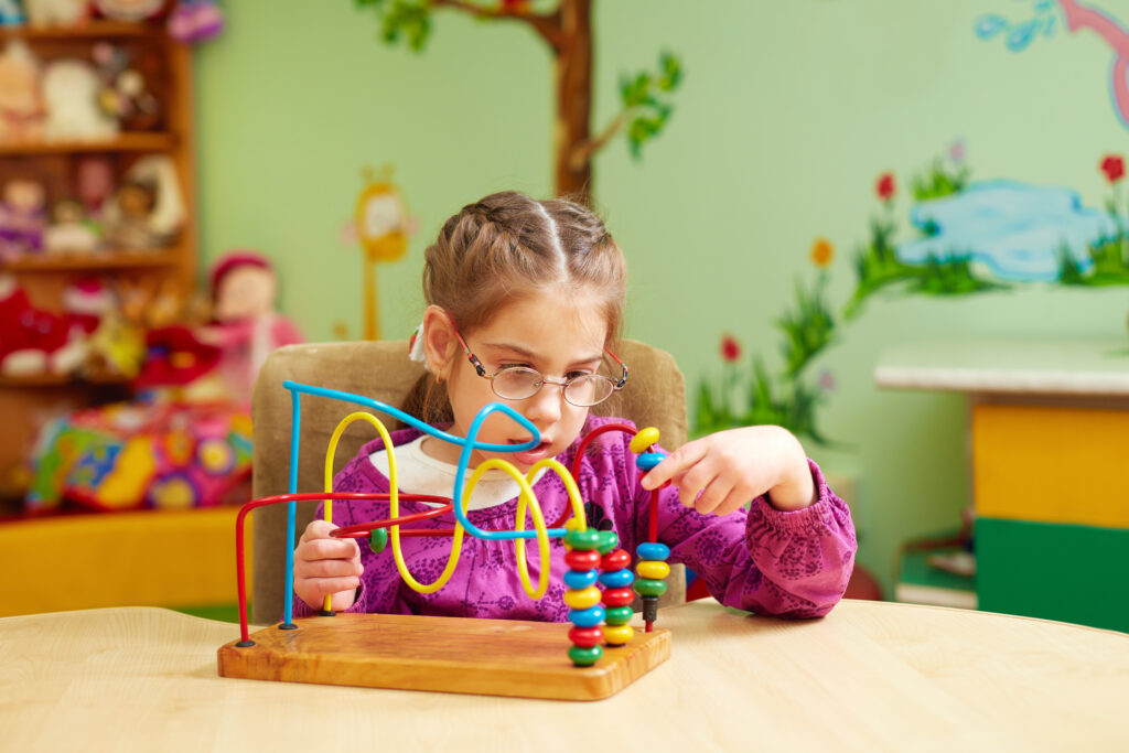 Little girl playing with toys at a special needs daycare.