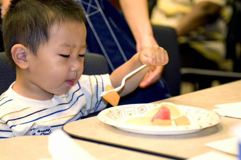 Cute young boy eating 4 Ways Our Daycare Offers Assistance for Feeding Disorders
