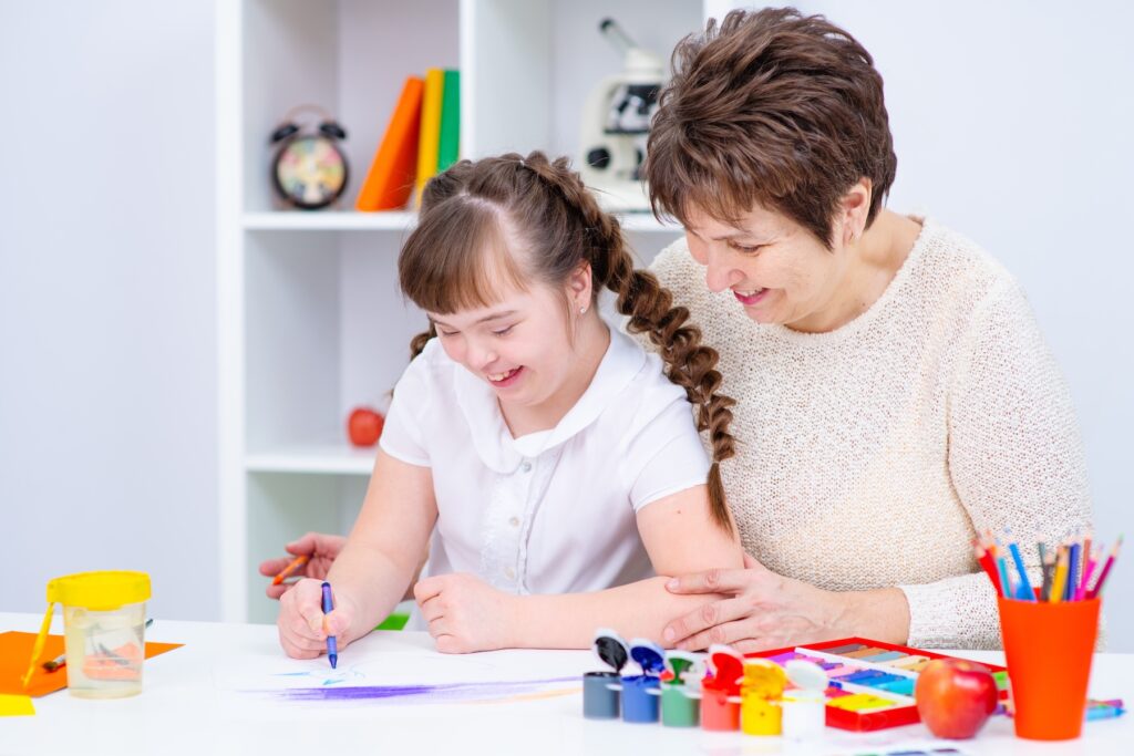 Girl with Down Syndrome engaged in creativity with her mother at home at the table