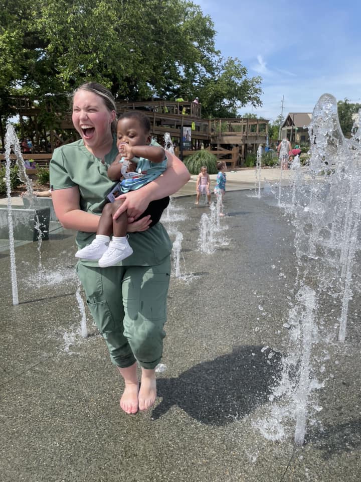 Skilled nurse playing with special needs child at a splash pad
